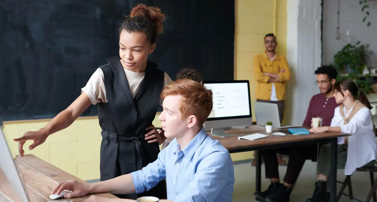 Équipe collaborant autour d'un ordinateur en bureau moderne.