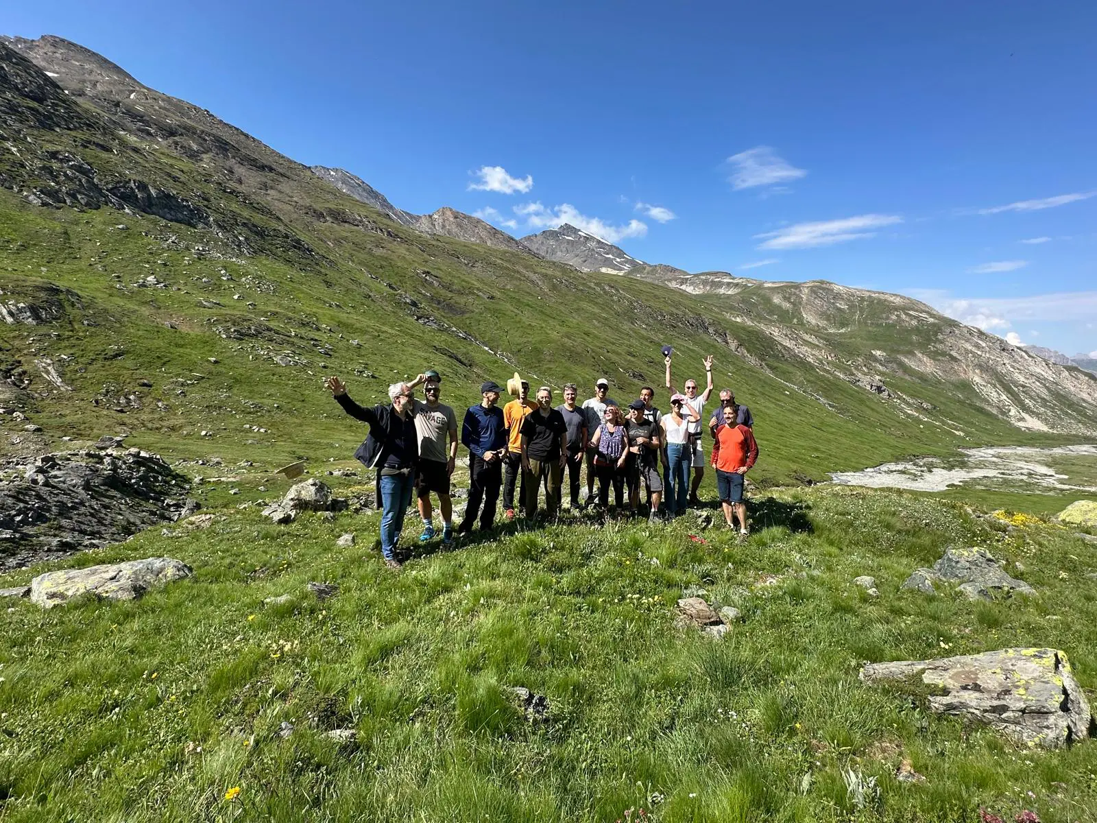 Groupe en randonnée dans montagnes verdoyantes, ciel bleu.