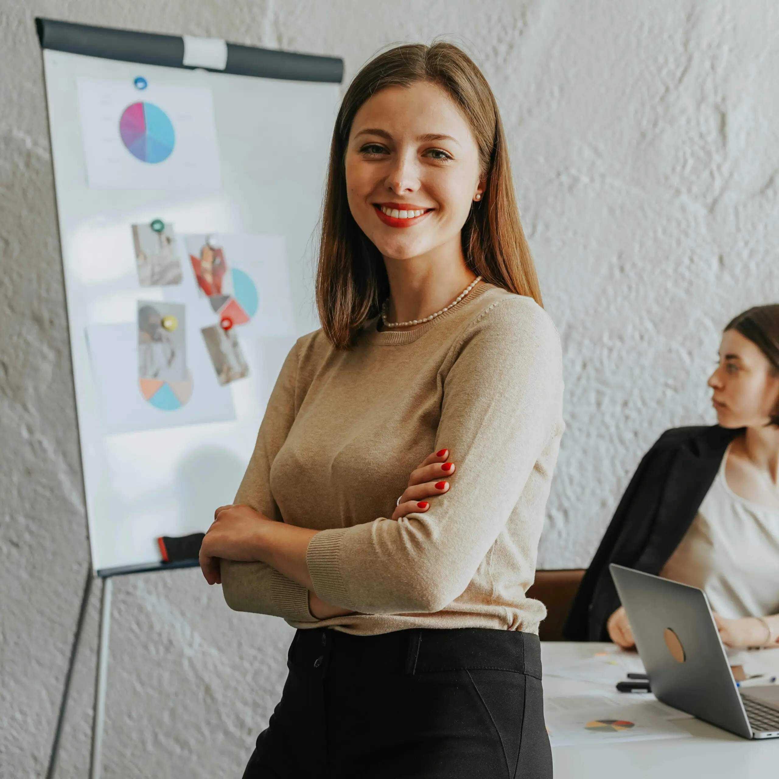 Femme souriante devant tableau graphique en réunion.