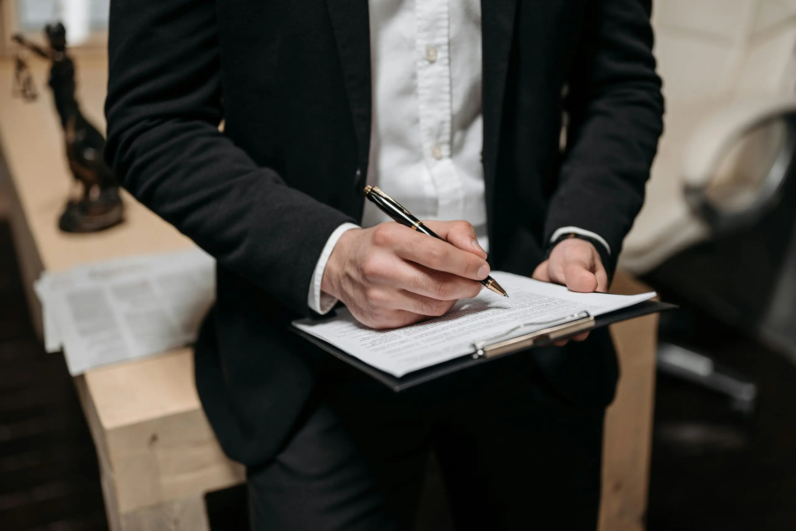 Homme signant un document sur une planchette.