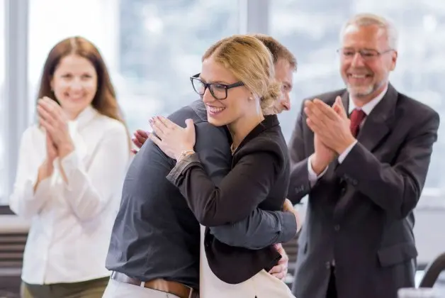 Célébration d'équipe avec étreinte au bureau.